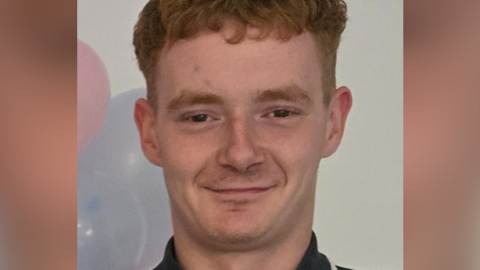 Family photo of Cain Parker wearing a polo shirt with balloons behind him