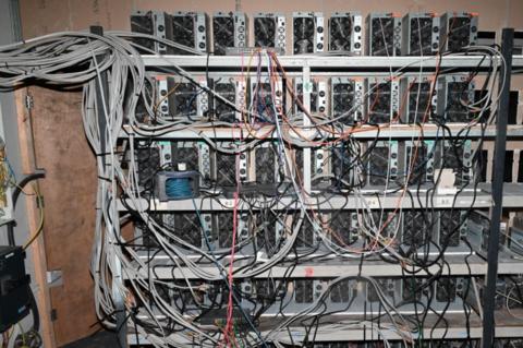 A series of machines being used to mine cryptocurrency. A series of wires are protruding from the machines.