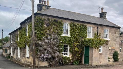 A Georgian building covered in wisteria 