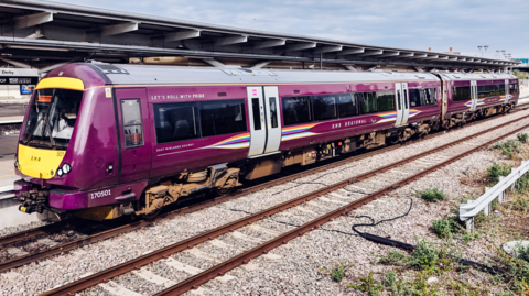 A purple East Midlands Railway train at a railway station in Derby.
