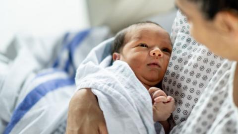 A newborn baby in a mother's arms