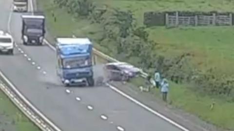 A lorry crashing into a car on the side of a dual carriageway