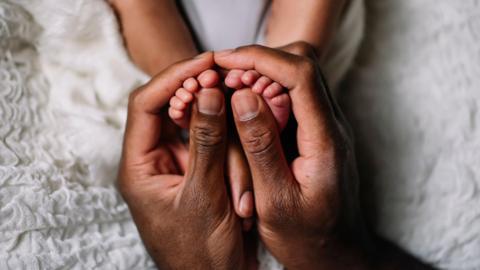 A close-up of a father hand holding a baby feet