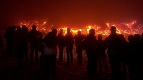 Line of people standing in front of lava flow