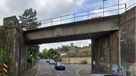 The Portway Overbridge over the A362, several cars are driving underneath the bridge. 