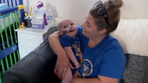 Mum in blue t-shirt holding baby son in matching t-shirt.