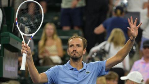 Daniil Medvedev holds up a tennis racquet