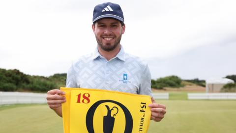 David Howard holds a yellow Open Championship flag after qualifying for this year's tournament at Royal Birkdale