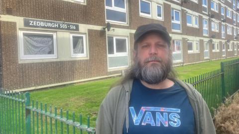 Phototgraph of Andy Roche, who lives on the Lower Falinge estate in Rochdale. He is pictured outside the Zedburgh block of maisonettes where lives.