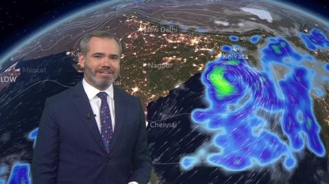 Ben Rich in front of a ˿ Weather map showing heavy rain in the Bay of Bengal