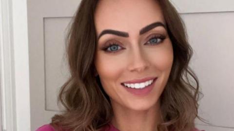 Rachel Borthwick smiling at the camera. She has brown hair and is wearing a pink t-shirt.