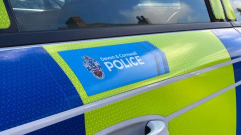A Devon and Cornwall Police car door, blue and yellow, seen close up.