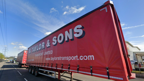 A red lorry trailer with large red writing which reads: "B Taylor & Sons Transport Limited".