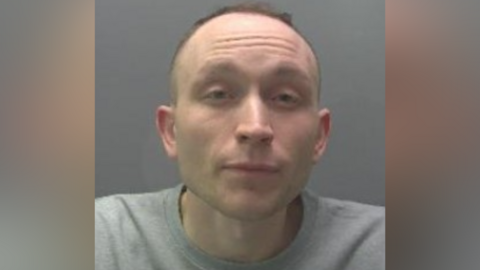 Custody image of Gregory Coulson - he is wearing a grey jumper and his hair is receding