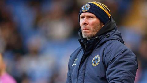 Shrewsbury Town manager Michael Appleton in his club beanie standing on the touchline