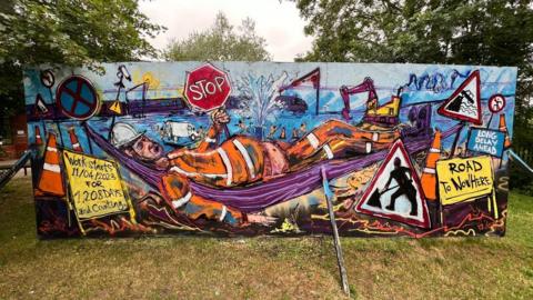 A picture of a mural with a workman lounging on a hammock and holding up a Stop sign