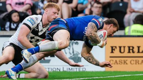 Wakefield Trinity's Tom Johnstone crashing over to score under pressure from Hull FC's Harvey Barron.
