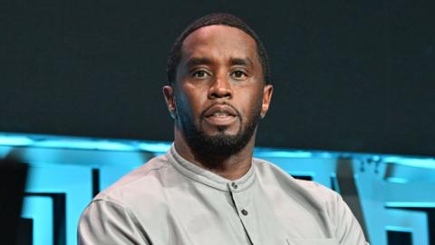 Sean Diddy Combs wears a grey shirt and has a blank expression