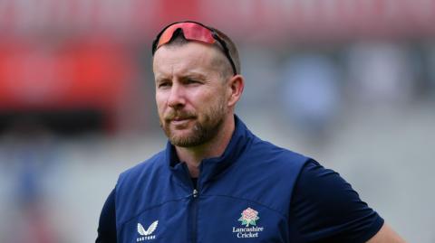 Steven Croft wearing a navy blue Lancashire gilet and with sunglasses perched on top of his head 