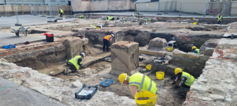 Archaeological wearing yellow and orange hi-vis jackets and yellow hard hats digging at the former Weymouth Bowl site in Dorset.