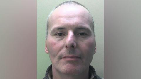 A police mugshot of Andrew Page who is balding with grey hair