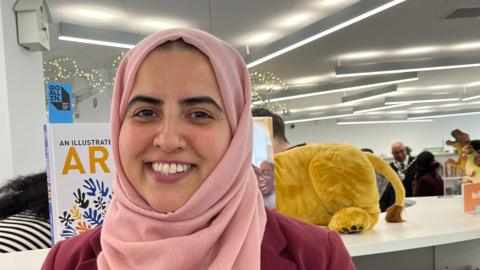 A woman inside the library smiling