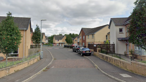 A street of modern houses with cars parked on the pavement