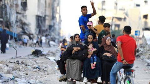 Palestinians travel on a donkey-pulled cart along a street in north-western Gaza City (9 July 2024)