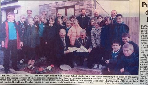 An article in a newspaper showing primary school children with notable members of the parish council and the head teacher with a box and letter going inside.