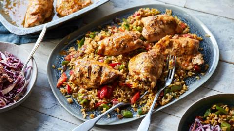 A large blue plate topped with rice and vegetables and five pieces of chicken.