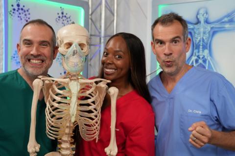 Doctor Chris and Xand with another doctor, standing next to billy bones the skeleton model