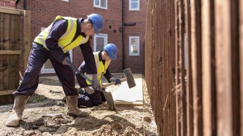 Builders in blue boiler suits working on a housing project