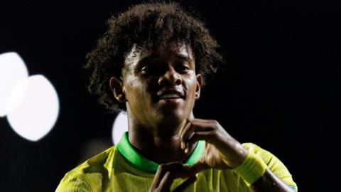 A close-up of Bruno Alves, wearing his yellow and green Brazil Under-20's kit, making a gesture with his hands to the crowd during the international youth side's game against Paraguay in March