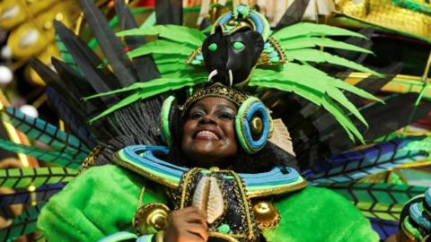 A reveller from Beija-Flor samba school performs, wearing bright green weathers and a headdress resembling a black panther, performs at the Sambadrome during Carnival in Rio de Janeiro on 4 March, 2025