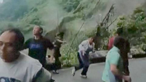 People seen running from a landslide is triggered by heavy rain in southern China