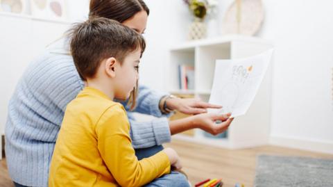 Young woman holding a picture conducting child's psychological test. 