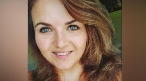 A closeup of a woman with brown hair smiling at the camera. 