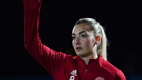 Maddy Cusack in a red Sheffield United jacket with her arm in the air