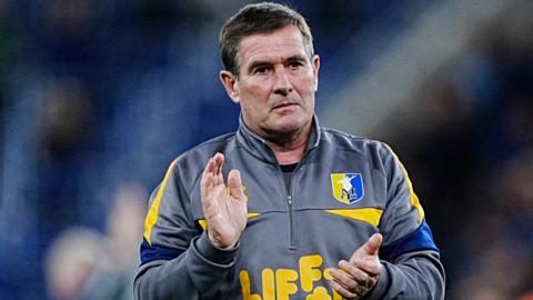 A sombre-looking Mansfield Town manager Nigel Clough applauds the club's 6,000 travelling supporters after his side's EFL Cup defeat at Everton.