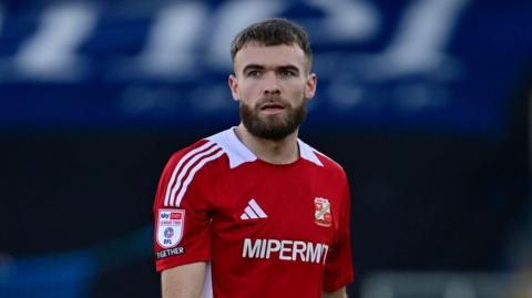 Aaron Drinan standing on the pitch with his arms by his side during a match for Swindon