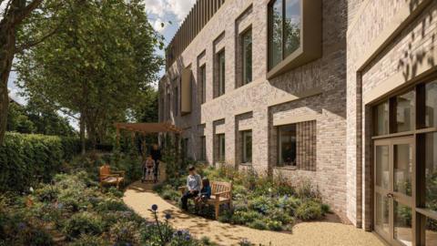A computer generated image showing plans for a new cancer care centre. It shows the outside of a building with brown bricks, a number of windows and a door. There are two benches outside in a garden with two seat sat on one on the benches and a person being pushed in a wheelchair along a path