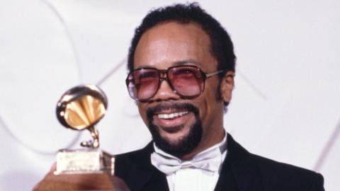 Quincy Jones holding up a Grammy Award in 1982