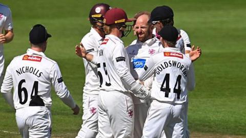 Somerset players gather round Jack Leach after a wicket