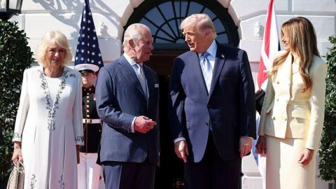Queen Camilla, King Charles, President Donald Trump and First Lady Melania Trump stand in line, with the King and Trump conversing, while Melania smiles at the two. 