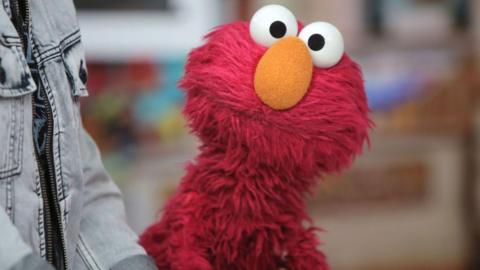 Red puppet Elmo stares into the camera