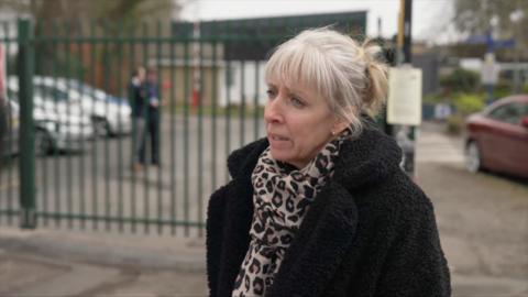 A woman with white hair looks to the left of the camera