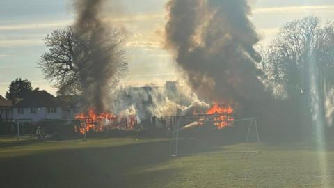 Smoke and flames at a fire in a sports pavilion in a field