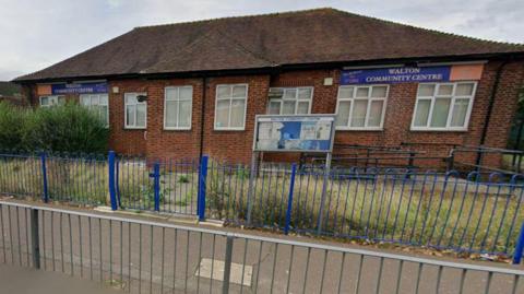 Exterior of the centre- a brick building with purple signage outside.