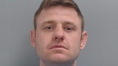 Mugshot of Liam Evans. He has very faint stubble and short fair hair.
