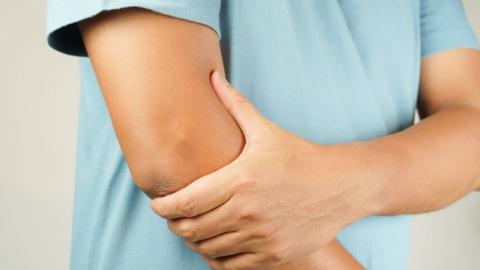 A person clutches their elbow with their opposite hand.